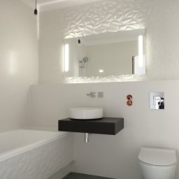 Baufirma Orczykowski - Nowoczesna łazienka w jasnych barwach z geometrycznym wzorem na ścianie, podświetlanym lustrem, okrągłą umywalką na czarnym blacie i wiszącą toaletą.