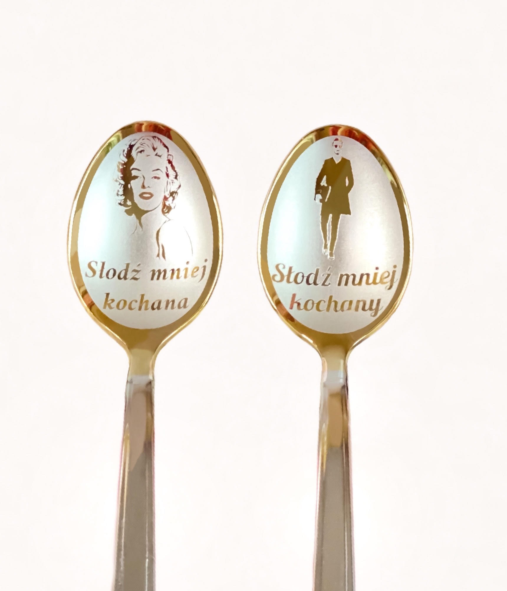 Dwie łyżeczki z grawerem: portret Marilyn Monroe i sylwetka mężczyzny w płaszczu, z napisem 'Słodź mniej kochana', prezent od firmy z Wrocławia.