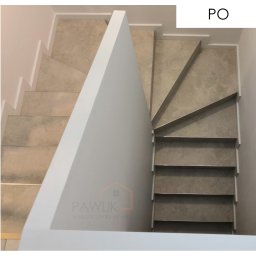 Schody zabiegowe obłożone gresem i białą listwą przypodłogową. 