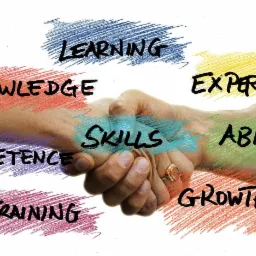 Uścisk dłoni z nałożonymi słowami: Learning, Knowledge, Competence, Training, Skills, Ability, Experience, Growth, symbolizujący rozw&oacute;j i wsp&oacute;łpracę.