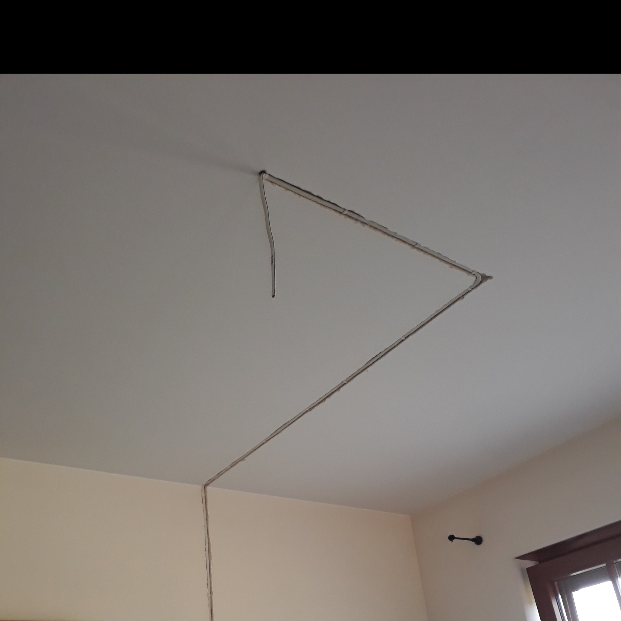 Przygotowanie do montażu instalacji elektrycznej w suficie podwieszanym z płyty karton gips, widoczne wycięte rowki na przewody i wystające kable.