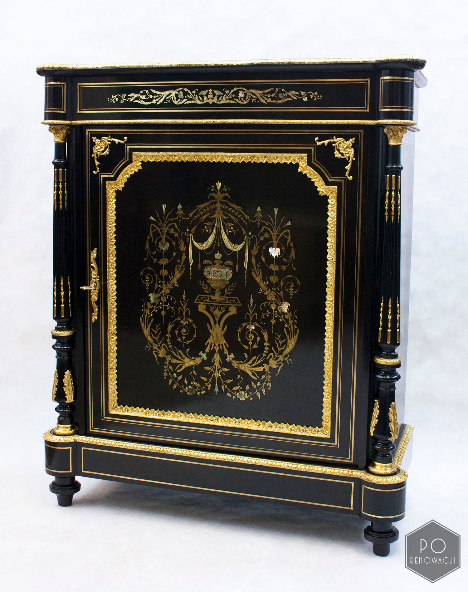 Elegancka, czarna szafka z dekoracyjnymi, złoconymi ornamentami i intarsjami z masy perłowej, stylizowana na antyk.