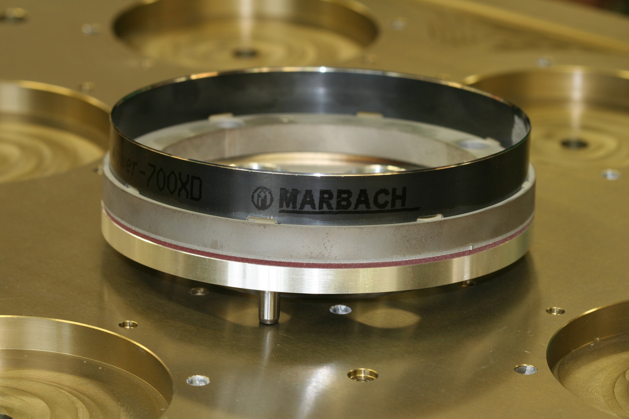 Precyzyjny, wieloelementowy pierścień z logo Marbach, zamocowany na metalowej płycie z otworami, widoczne oznaczenie 'ker-700XD'.
