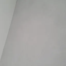 Ściana pomalowana na szaro z widoczną delikatną strukturą, narożnik sufitu pomalowany na biało.