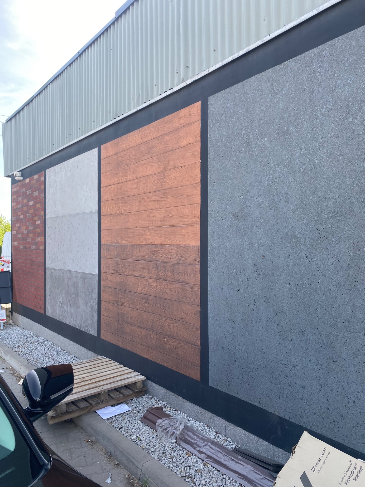 Ekspozycja fragmentów elewacji z różnymi fakturami: cegła, imitacja drewna, beton architektoniczny. Prezentacja materiałów wykończeniowych na zewnątrz budynku.