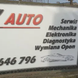 Baner reklamowy warsztatu BK AUTO z napisem 'Serwis Mechanika Elektronika Diagnostyka Wymiana Opon' i numerem telefonu, zawieszony na ogrodzeniu z siatki.