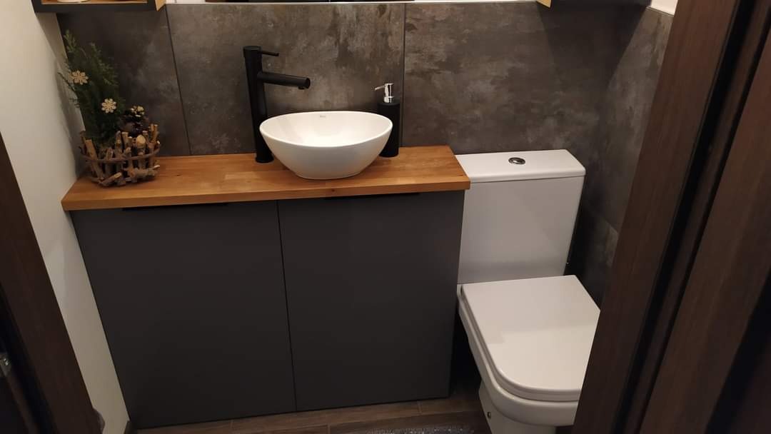 Nowoczesna łazienka w Charzykowach z umywalką nablatową w kształcie misy, osadzoną na drewnianym blacie i szarej szafce, obok toaleta i dekoracja roślinna.