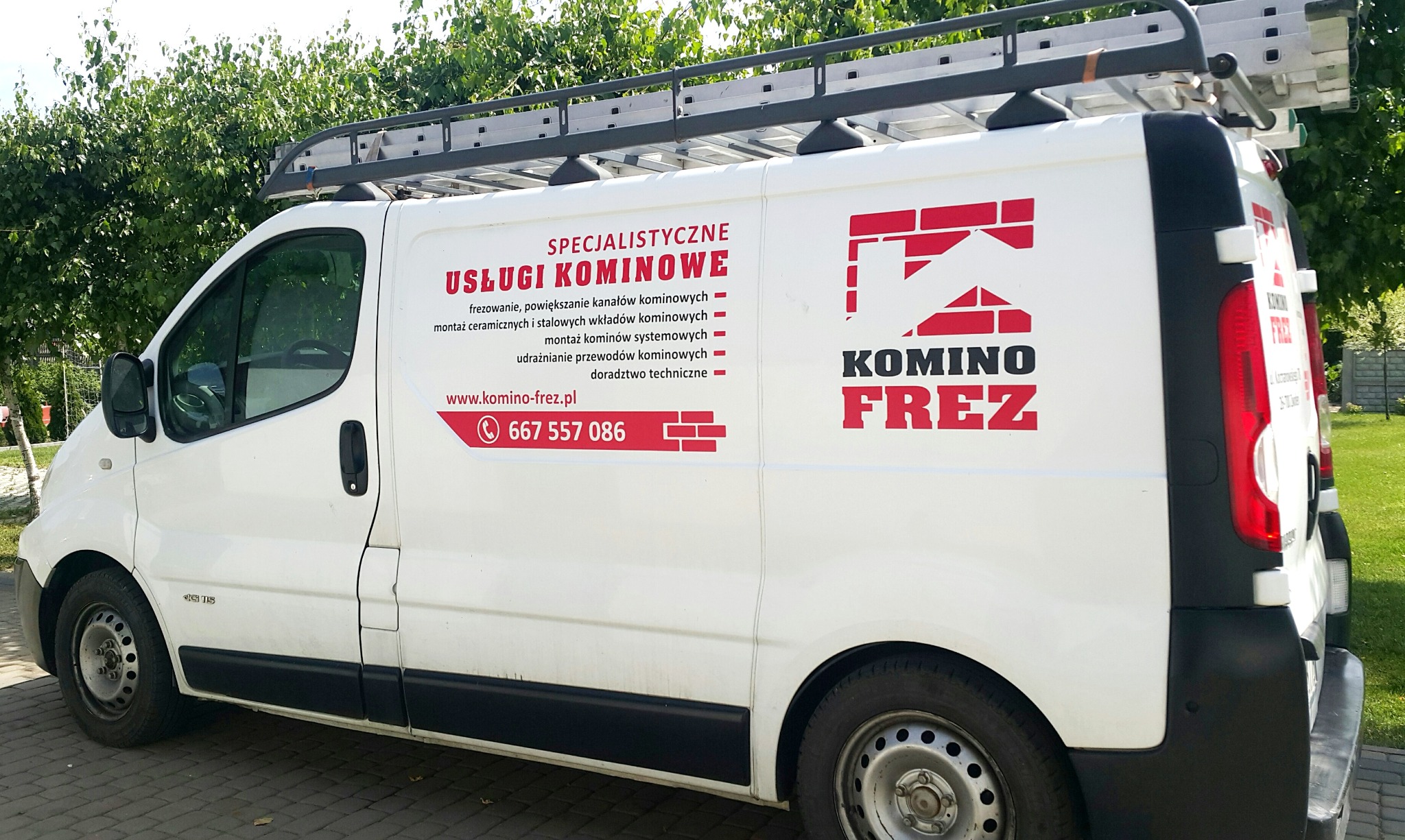 Biały van z drabiną na dachu, oklejony reklamą firmy specjalizującej się w usługach frezowania, montażu wkładów i udrażnianiu przewodów kominowych, z widocznym numerem telefonu i adresem strony...