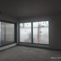 Wnętrze pokoju po nałożeniu tynków maszynowych, okna zabezpieczone folią, widoczne worki z zaprawą Baumit na podłodze.