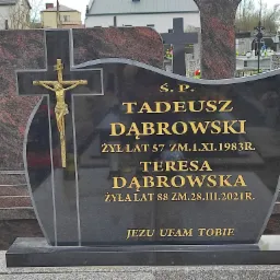 Czarny, granitowy nagrobek z krzyżem i figurą Chrystusa, z wygrawerowanymi złotymi literami informującymi o zmarłych Tadeuszu i Teresie Dąbrowskich, na tle cmentarza.