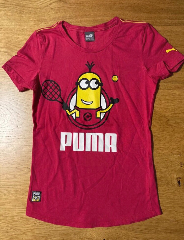 Czerwona damska koszulka Puma z nadrukiem Minionka grającego w tenisa na drewnianym tle.
