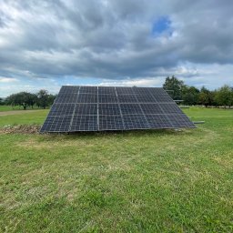 LDR Electrical Dariusz Karaś - Panel słoneczny ustawiony na trawiastym polu pod pochmurnym niebem, widoczne drzewa w tle.