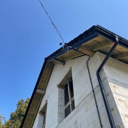 LDR Electrical Dariusz Karaś - Surowy stan domu w budowie z widocznym przyłączem kablowym do budynku, czarną rynną i niezabudowanymi otworami okiennymi.