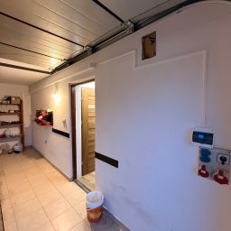 LDR Electrical Dariusz Karaś - Gniazda siłowe i skrzynka elektryczna na ścianie w garażu w Jaśle. Widoczne przewody i instalacja elektryczna. Prace wykończeniowe.