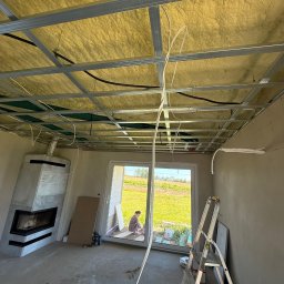 LDR Electrical - Montaż sufitu podwieszanego z izolacją i instalacją elektryczną w nowym domu. Widoczny kominek i drabina.