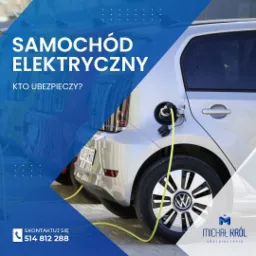 Samochód elektryczny podłączony do ładowania w Żurominie, widok z tyłu, z widocznym kablem ładowania i fragmentem logo firmy ubezpieczeniowej.