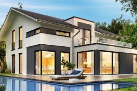 Nowoczesny dom jednorodzinny z płaskim dachem i dużymi oknami, z basenem na pierwszym planie i leżakiem na drewnianym tarasie.