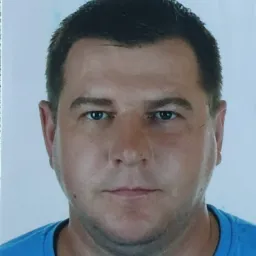 Portret mężczyzny w niebieskiej koszulce na jasnym tle.