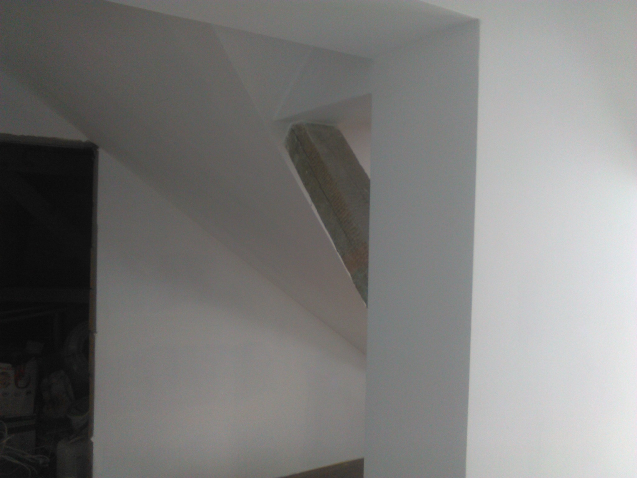 Skośna ściana poddasza z elementami konstrukcyjnymi obudowanymi płytami gipsowo-kartonowymi, przygotowana do dalszego wykończenia.