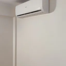 Biały klimatyzator Heko zamontowany na jasnej ścianie w pomieszczeniu, widoczna instalacja elektryczna z wtyczką w gniazdku.