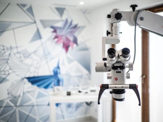 Mikroskop stomatologiczny Leica w nowoczesnym gabinecie z geometrycznym wzorem na ścianie.