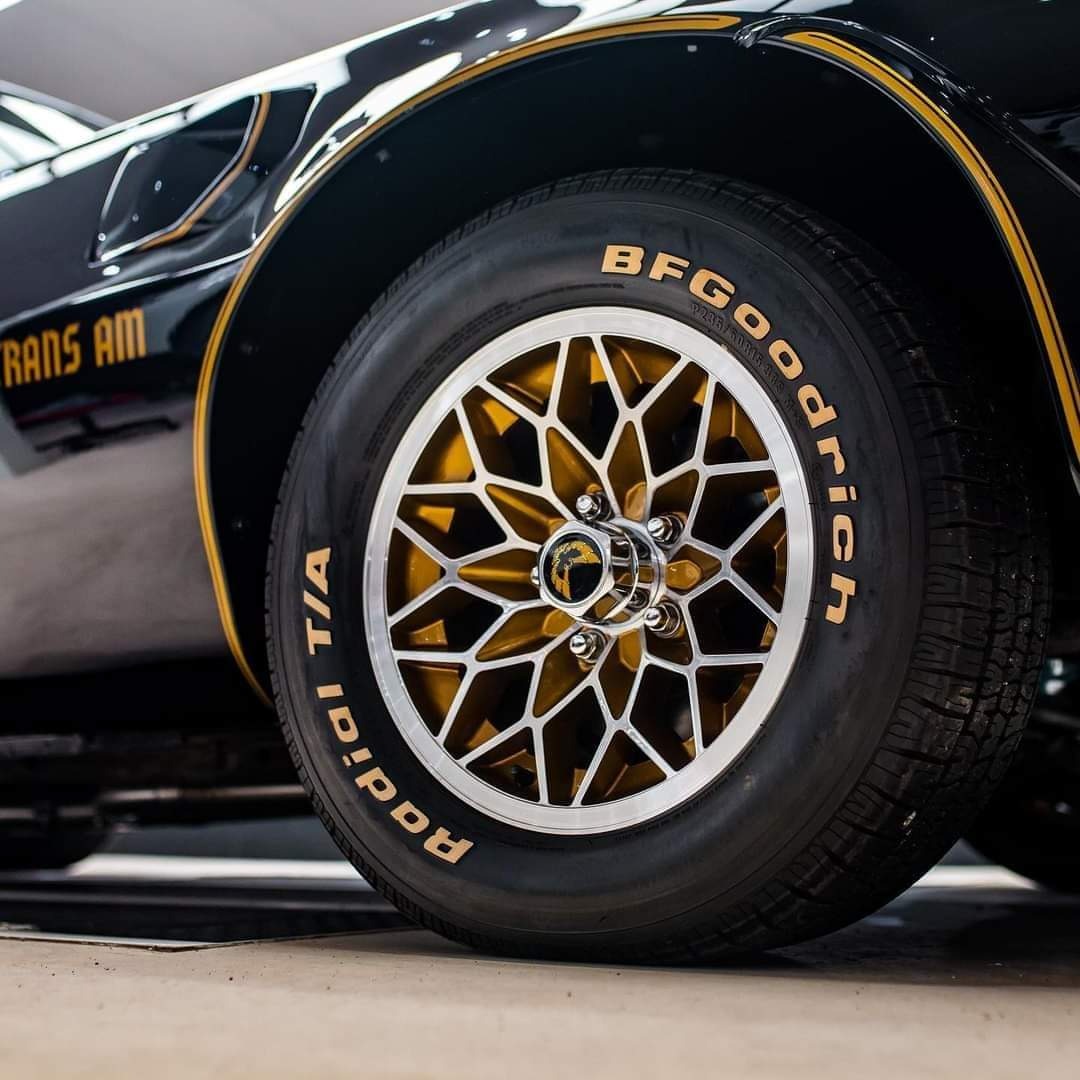 Czarny samochód Trans Am z widocznym złotym paskiem, felgami w kształcie gwiazdy i oponami BF Goodrich Radial T/A.