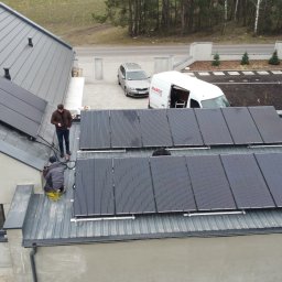 Auto-Maro Sp. z o.o. - Montaż paneli słonecznych na dachu domu jednorodzinnego z widocznym samochodem i busem firmy instalacyjnej na posesji.