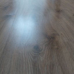 Impuls Energia - Ułożone panele podłogowe w odcieniach brązu, z widoczną strukturą drewna i delikatnym połyskiem, sfotografowane pod kątem, ukazujące perspektywę podłogi.