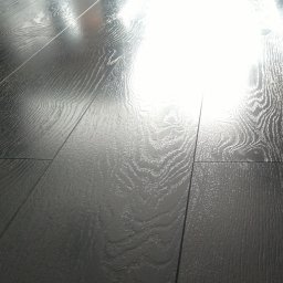 Impuls Energia - Połyskująca, ciemna podłoga z paneli z wyraźnym rysunkiem drewna, oświetlona padającym światłem, ukazująca precyzję ułożenia i estetyczny wygląd.