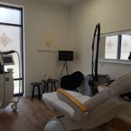 Jasne wnętrze gabinetu z fotelem zabiegowym, urządzeniem LPG i logo 'BEAUTIFULLIFE' na ścianie i oknie.