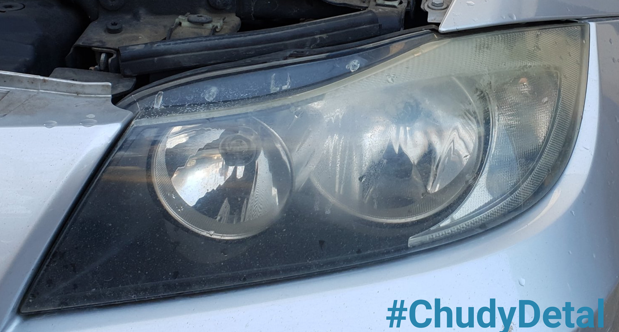 Mętny reflektor srebrnego samochodu przed polerowaniem, widoczne zarysowania i zabrudzenia, zbliżenie na przedni reflektor.