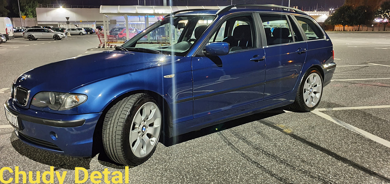 Niebieskie BMW E46 kombi po detailingu, zaparkowane na parkingu pod marketem, widoczne ślady opon na asfalcie.