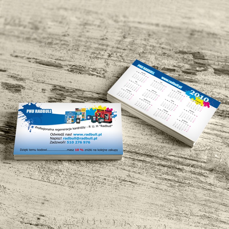 Stos wizytówek i kalendarzyków firmowych PHU Radbull na teksturowanym, jasnym tle. Wizytówka z logo i informacjami kontaktowymi, kalendarzyk z rokiem 2010.