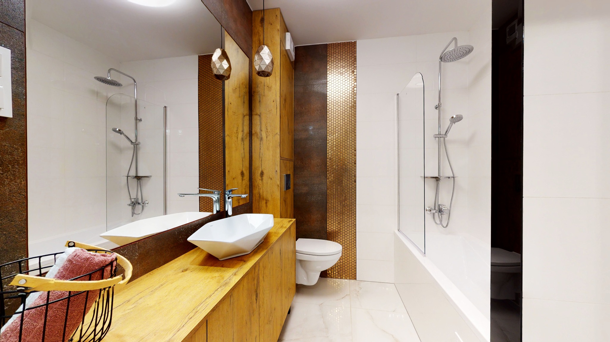 Nowoczesna łazienka z białymi płytkami, drewnianą szafką pod umywalkę w kształcie diamentu i złotymi akcentami na ścianie oraz wiszącymi lampami.