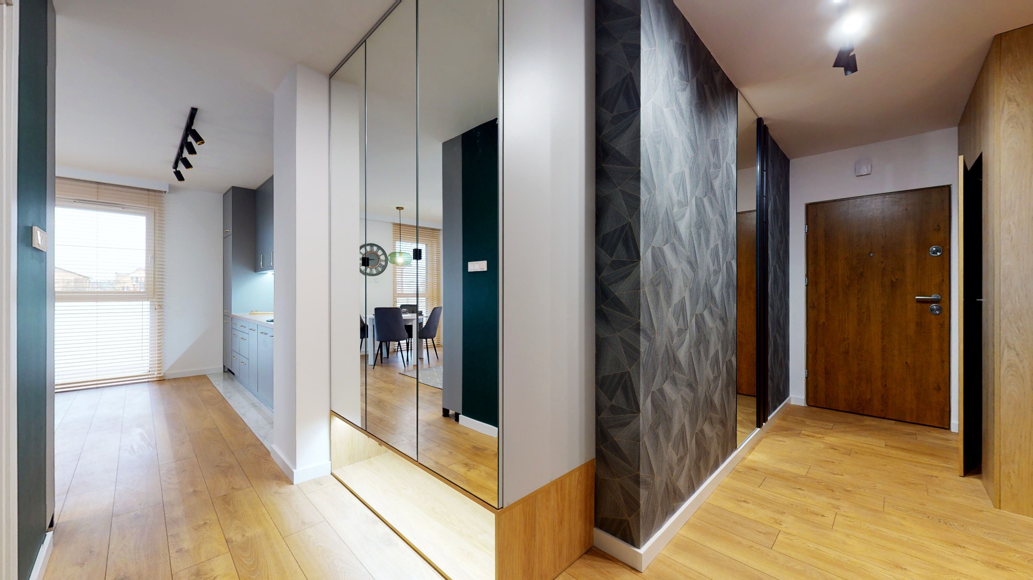 Nowoczesny przedpokój z lustrzaną szafą wnękową, podświetlaną półką, panelami ściennymi z geometrycznym wzorem i drewnianymi drzwiami wejściowymi.