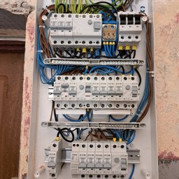 PE - Smart Home - Rozdzielnica elektryczna Eaton w trakcie montażu w Warszawie. Widoczne bezpieczniki, przewody i listwy zaciskowe. Instalacja w surowym wnętrzu.