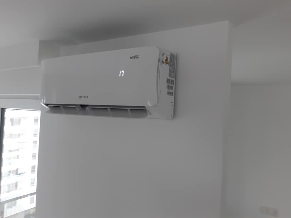 Biały klimatyzator ścienny z wyświetlaczem temperatury ustawionej na 17 stopni, zamontowany w nowym, jasnym pomieszczeniu z widokiem na miasto za oknem.