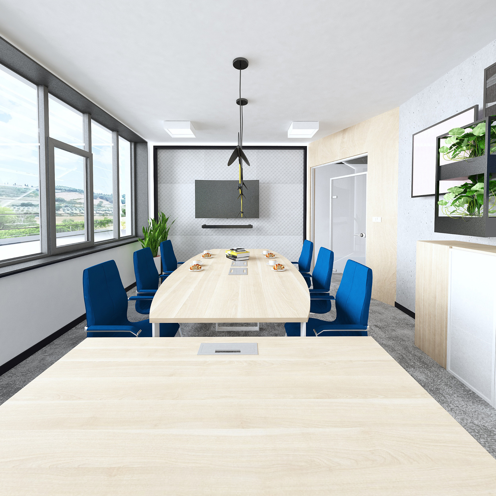 Nowoczesna sala konferencyjna z owalnym stołem z jasnego drewna, otoczonym niebieskimi krzesłami, podwieszana lampa z elementami żółtymi, monitor na ścianie z wzorem, widok na zewnątrz przez duże...