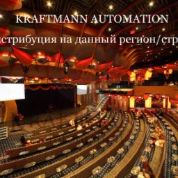 Wnętrze sali widowiskowej z rzędami foteli, oświetleniem w odcieniach czerwieni i ekranem projekcyjnym na scenie. Widoczne osoby na widowni.