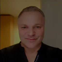 Portret mężczyzny w czarnej koszuli z wyhaftowanym imieniem i nazwiskiem DANIEL DAAG.