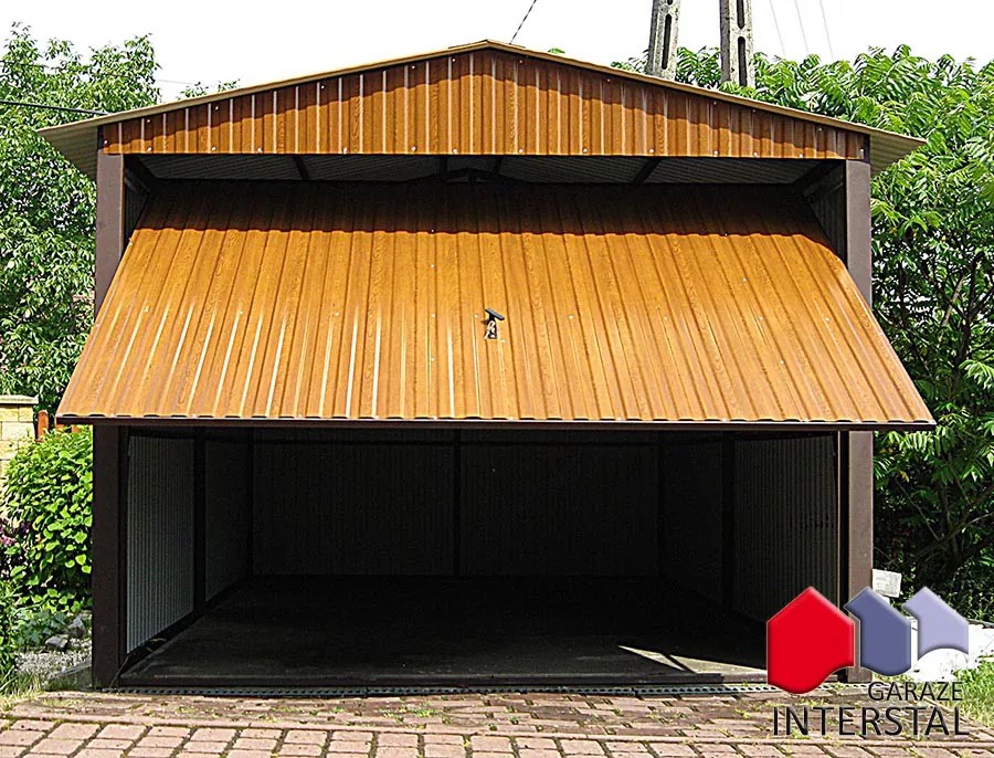 Otwarty garaż blaszany z brązową, imitującą drewno, blachą trapezową, widok z zewnątrz na pusty środek, na pierwszym planie kostka brukowa, w tle zieleń.