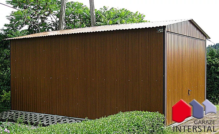 Brązowy garaż blaszany z dachem dwuspadowym, umieszczony na betonowej podmurówce, z logo firmy Interstal w prawym dolnym rogu.