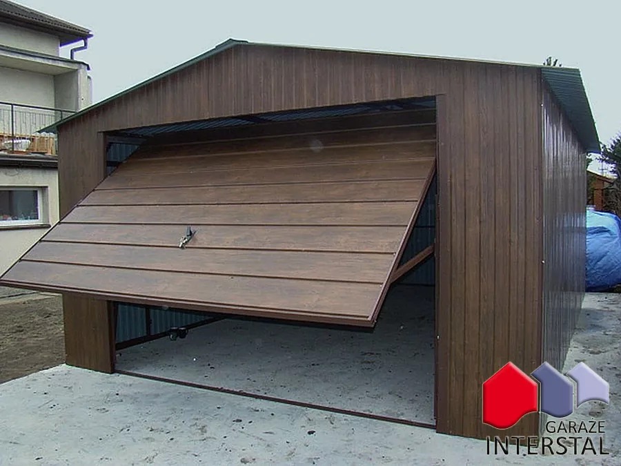 Otwarty garaż blaszany z brązową, segmentową bramą uchylną, widok z zewnątrz na betonową posadzkę wewnątrz.