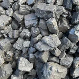 Kupa błyszczącego, czarnego węgla kamiennego o nieregularnych kształtach, oświetlona naturalnym światłem.