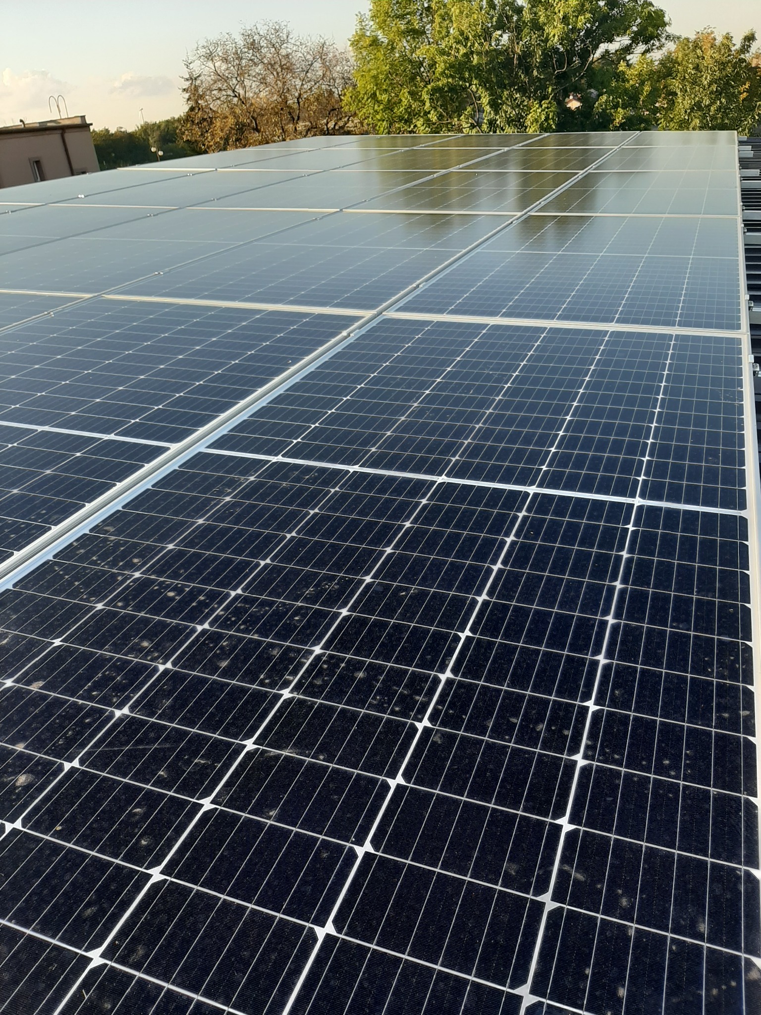 Panele słoneczne na dachu budynku w Kleczewie, widoczne zabrudzenia na powierzchni paneli.