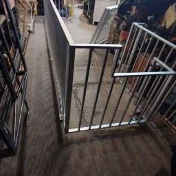 WoodProSteel - Wnętrze warsztatu z metalową balustradą schodową w trakcie produkcji, widoczne surowe wykończenie i narzędzia w tle.