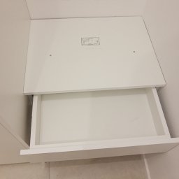 WREM SPÓŁKA Z OGRANICZONĄ ODPOWIEDZIALNOŚCIĄ - Otwarta, biała szuflada w szafie na wymiar, widoczna od góry, z delikatnym oświetleniem padającym na wnętrze. Na górnej płycie widoczna naklejka z numerem seryjnym.