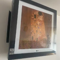Klimatyzator LG ARTCOOL Gallery z obrazem 'Pocałunek' Gustava Klimta, zamontowany na ścianie.