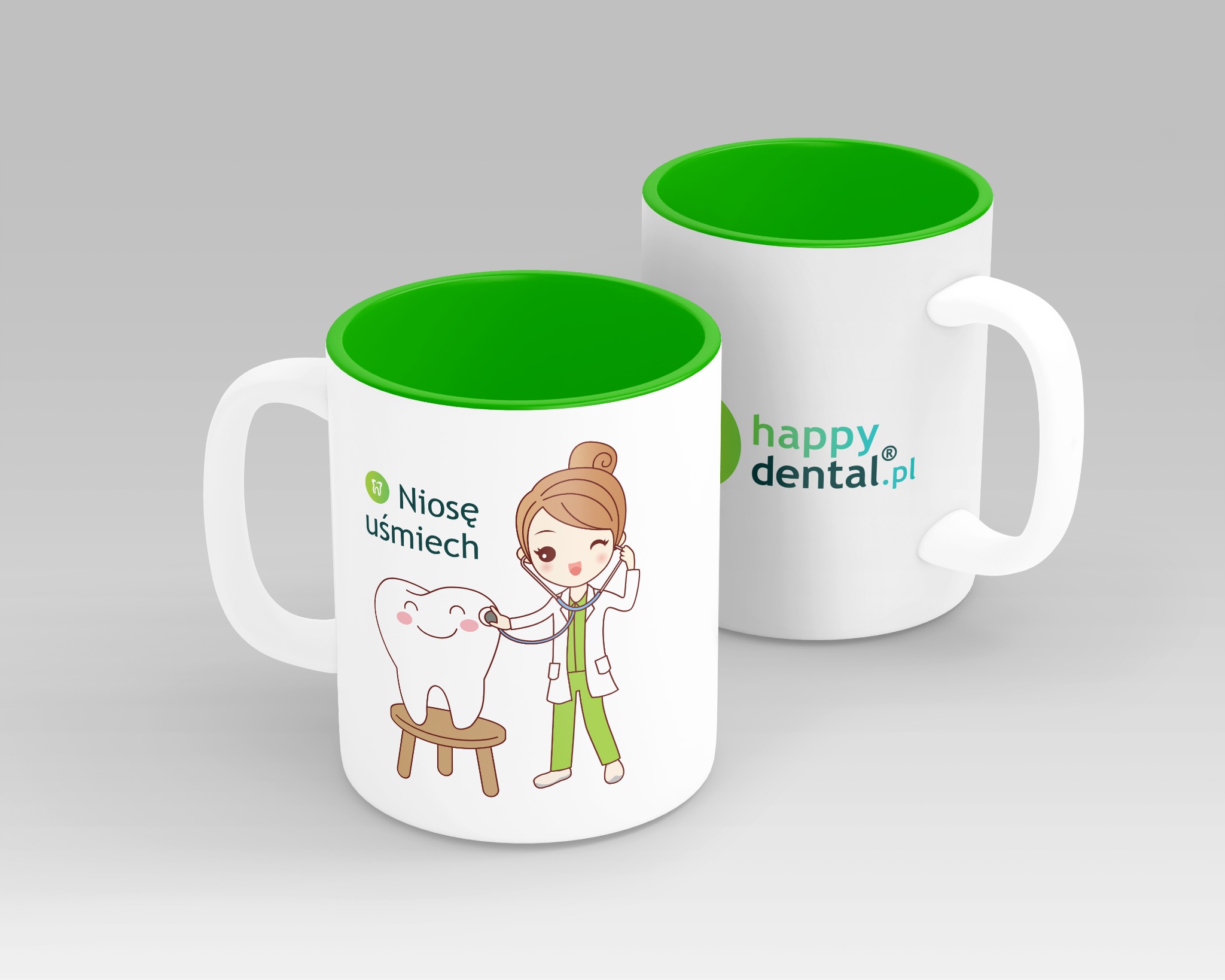 Dwa białe kubki z zielonym wnętrzem. Na jednym kubku rysunek uśmiechniętego zęba siedzącego na stołeczku, badanego przez uśmiechniętą postać w stroju lekarza. Obok napis 'Niosę uśmiech'. Na drugim...