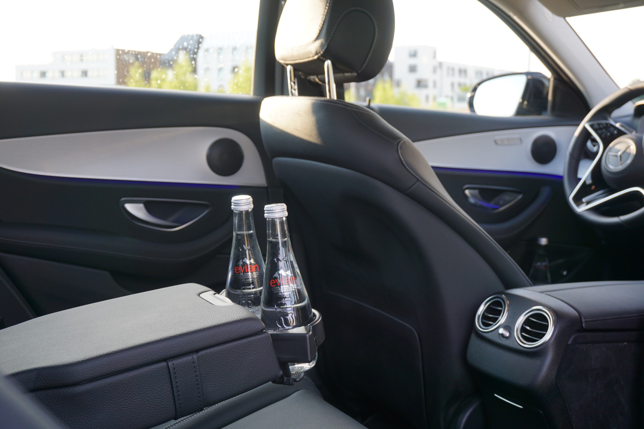 Wnętrze luksusowego samochodu z dwoma butelkami wody Evian w uchwycie, widok z tylnego siedzenia, Wrocław.